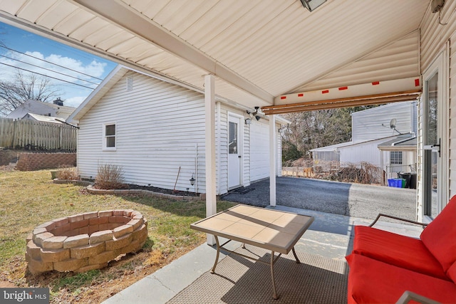 view of patio with an outdoor fire pit, a garage, and fence