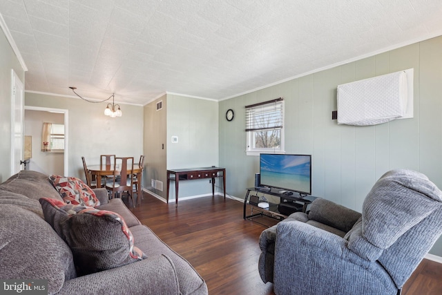 living area with visible vents, baseboards, ornamental molding, wood finished floors, and an inviting chandelier
