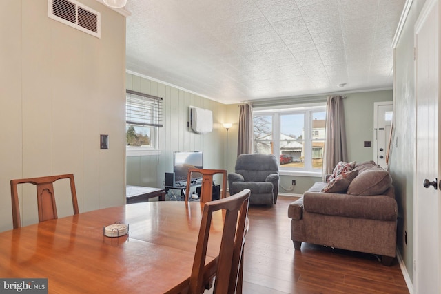 dining area featuring crown molding, dark wood-style flooring, baseboards, a textured ceiling, and visible vents