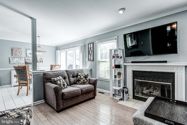 living room with crown molding, a fireplace with flush hearth, wood finished floors, baseboards, and a chandelier
