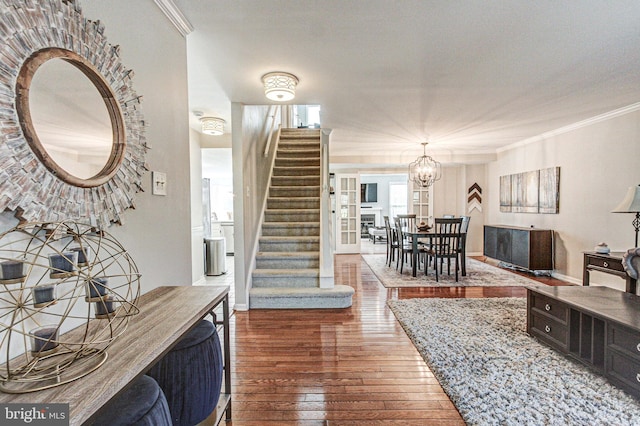 living area with crown molding, a chandelier, stairs, baseboards, and hardwood / wood-style flooring