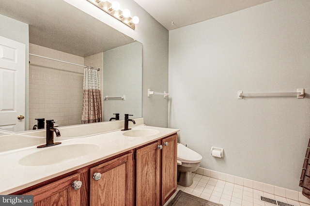 bathroom with a sink, tile patterned floors, toilet, and double vanity