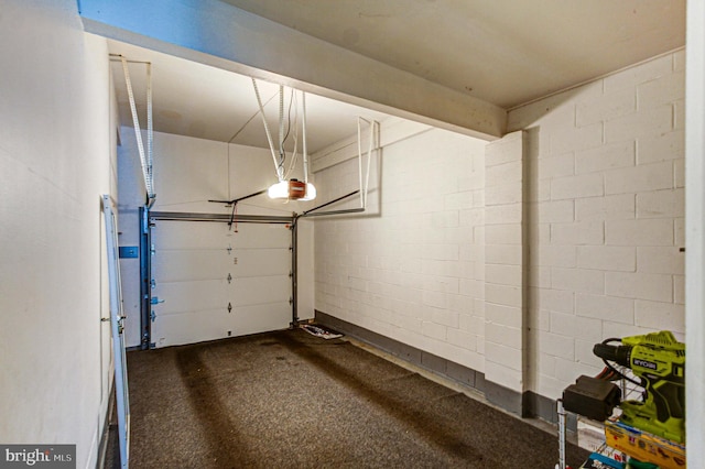 garage with a garage door opener and concrete block wall