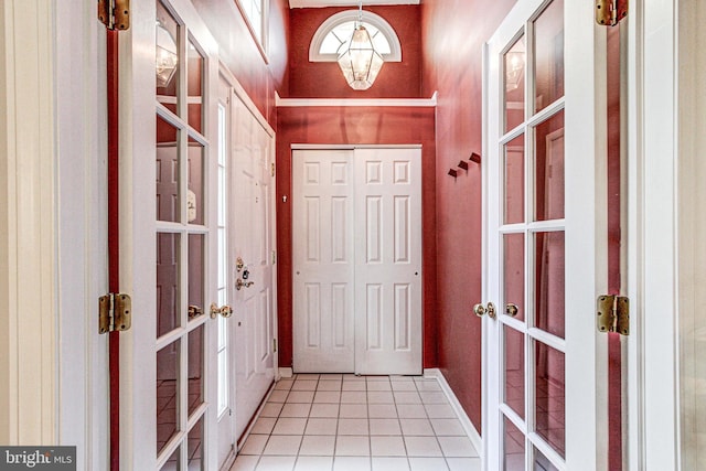 doorway with light tile patterned floors, french doors, and a chandelier