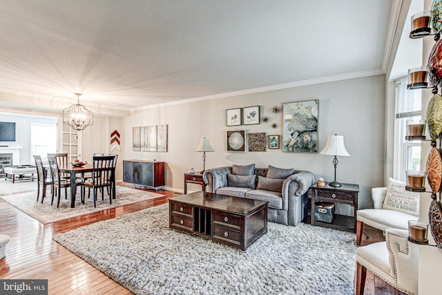 living area featuring ornamental molding, hardwood / wood-style floors, and a notable chandelier