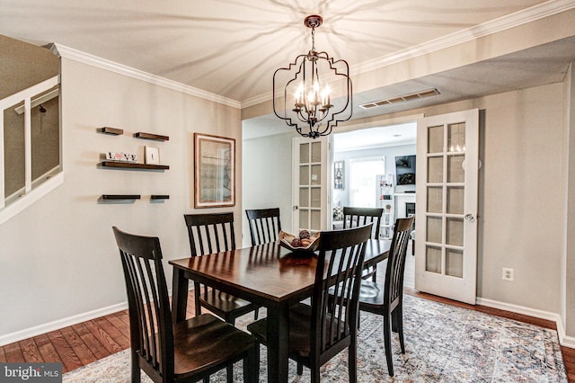 dining area with visible vents, baseboards, wood finished floors, and an inviting chandelier