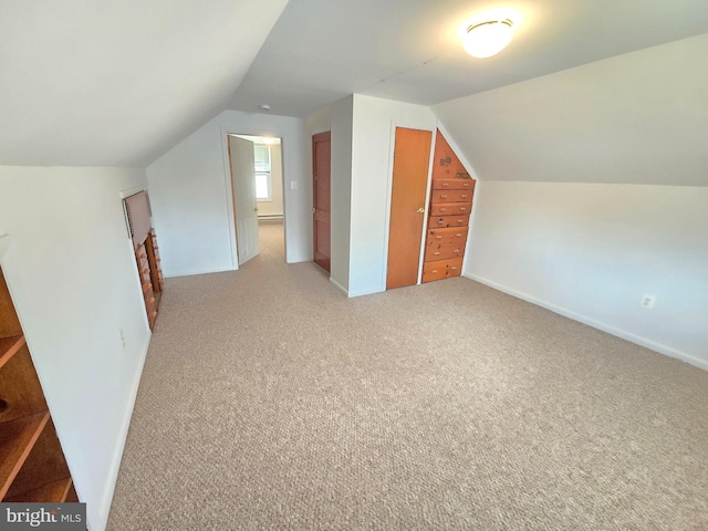 additional living space featuring lofted ceiling, baseboards, and light carpet