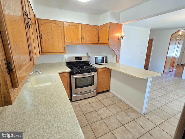 kitchen featuring a sink, stainless steel appliances, a peninsula, light tile patterned flooring, and light countertops