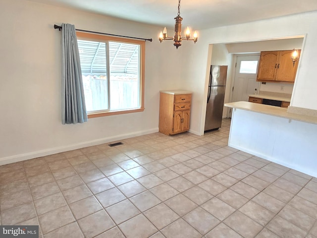 kitchen featuring light countertops, plenty of natural light, freestanding refrigerator, and a chandelier