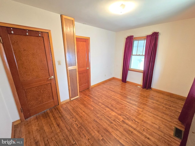 unfurnished bedroom with wood finished floors, visible vents, and baseboards