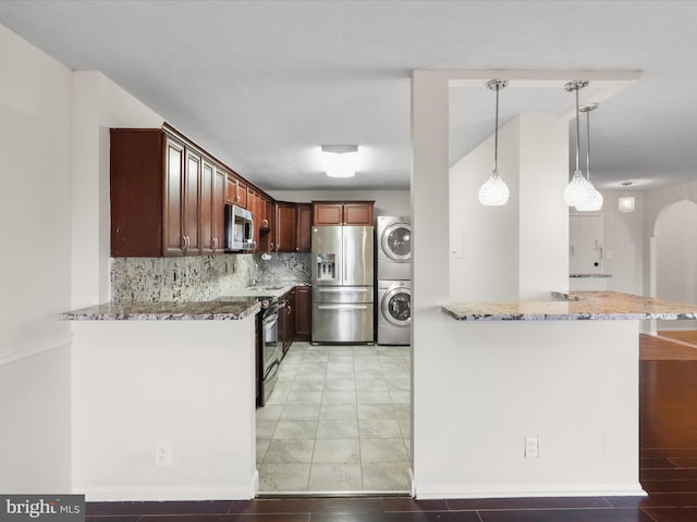 309 Yoakum Pkwy Unit 1003, Alexandria, VA 22304 - kitchen featuring light stone countertops, appliances with stainless steel finishes, a peninsula, stacked washer and clothes dryer, and arched walkways