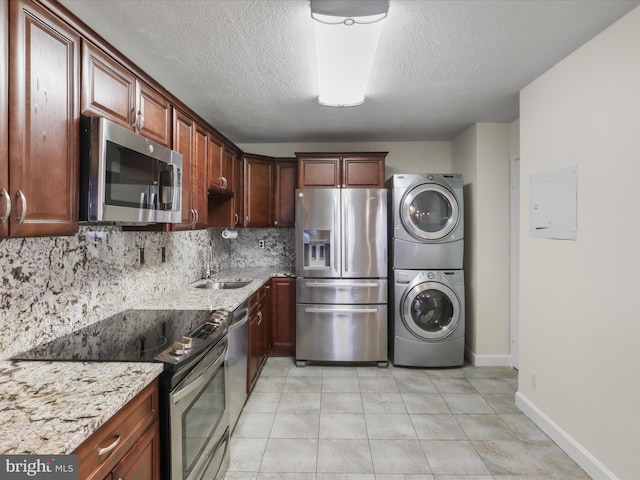 309 Yoakum Pkwy Unit 1003, Alexandria, VA 22304 - kitchen featuring backsplash, a sink, stacked washer / dryer, light stone countertops, and appliances with stainless steel finishes