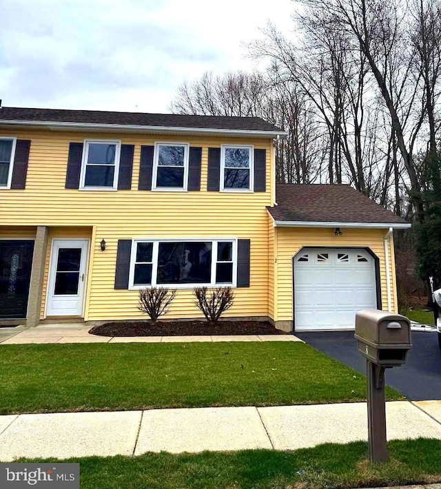 view of front of property featuring a front yard, a garage, and driveway