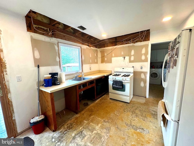 kitchen with washer and dryer, white appliances, light countertops, and a sink