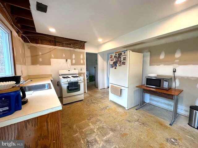 kitchen with a sink, white appliances, concrete floors, and light countertops