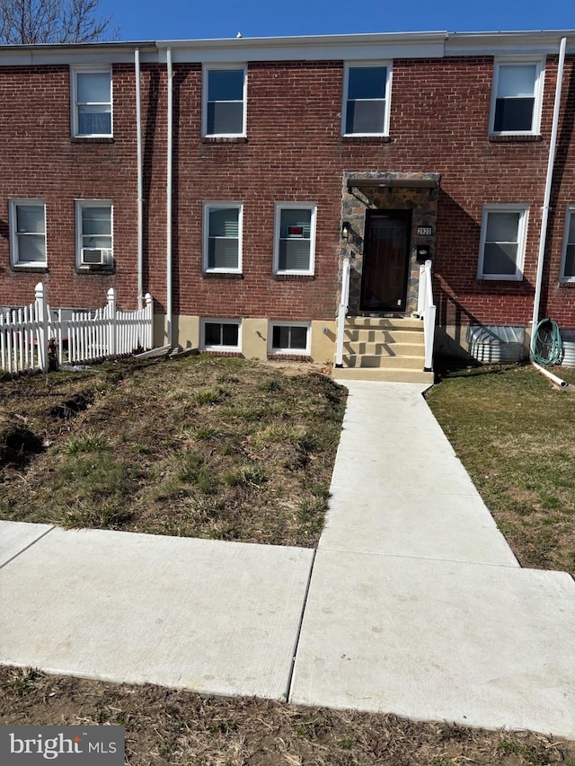 view of front of property with brick siding, cooling unit, and fence