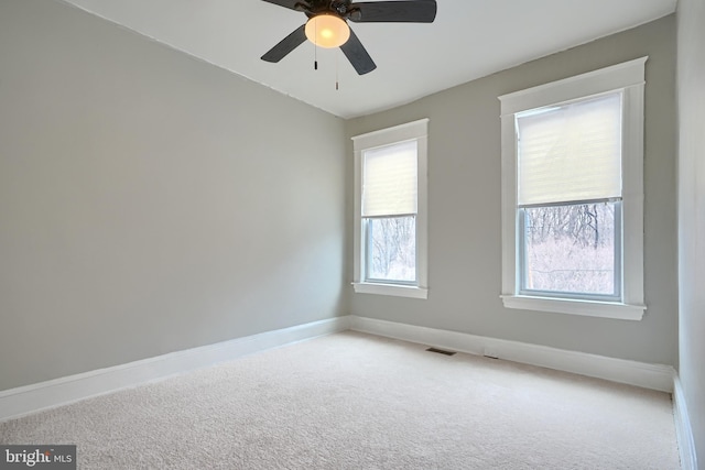 unfurnished room with visible vents, carpet flooring, a ceiling fan, and baseboards