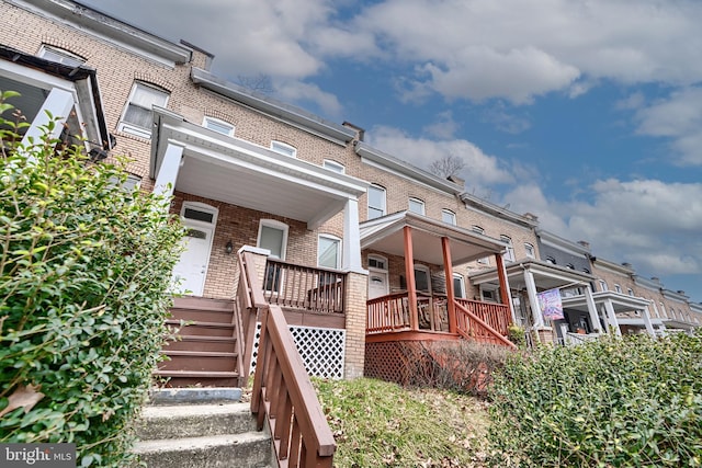 exterior space with brick siding, stairway, and covered porch