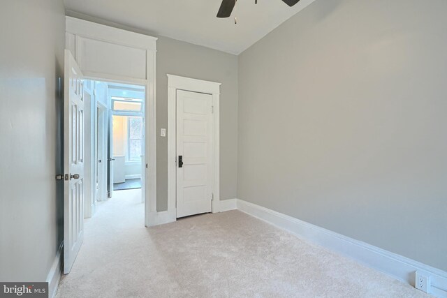 unfurnished bedroom featuring light colored carpet, baseboards, and ceiling fan