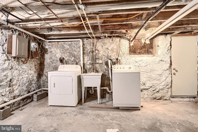unfinished below grade area featuring electric panel, washing machine and dryer, and a sink