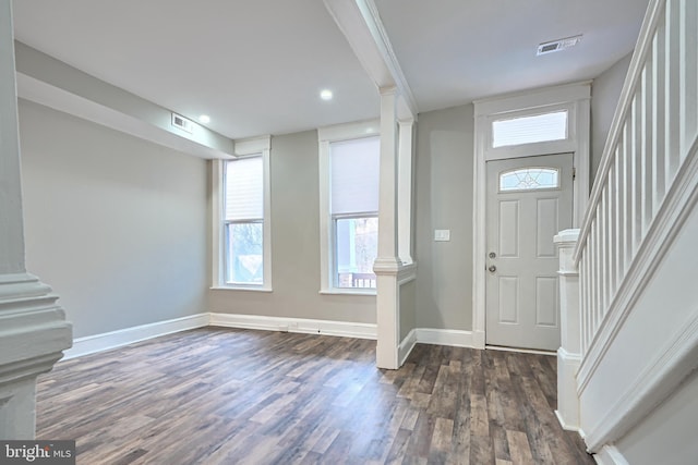foyer entrance featuring visible vents, dark wood finished floors, stairway, baseboards, and ornate columns