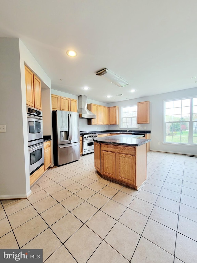 kitchen with dark countertops, wall chimney exhaust hood, appliances with stainless steel finishes, and light tile patterned floors