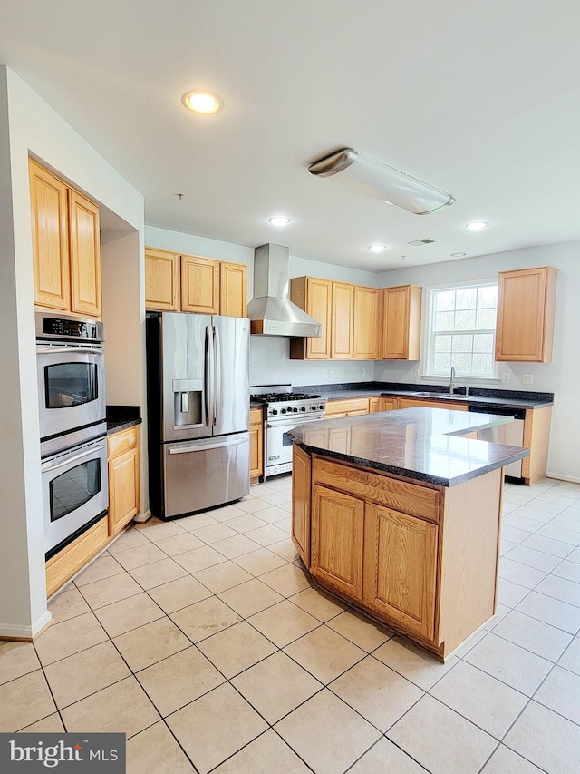 kitchen with wall chimney range hood, a sink, appliances with stainless steel finishes, and light tile patterned floors