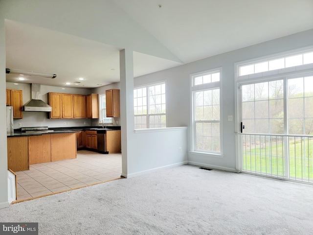 kitchen with light colored carpet, baseboards, dark countertops, appliances with stainless steel finishes, and wall chimney exhaust hood