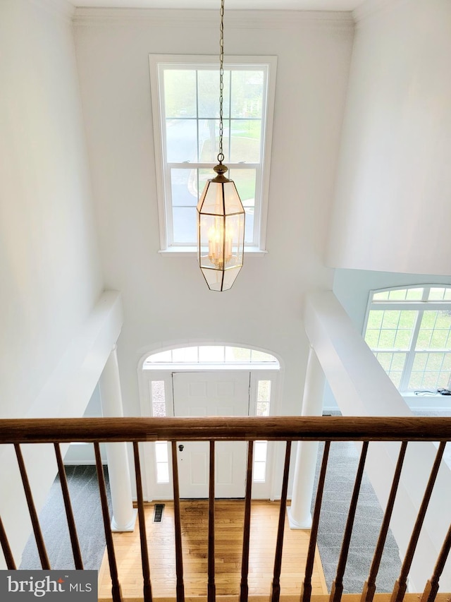 stairs with a notable chandelier, crown molding, and wood finished floors