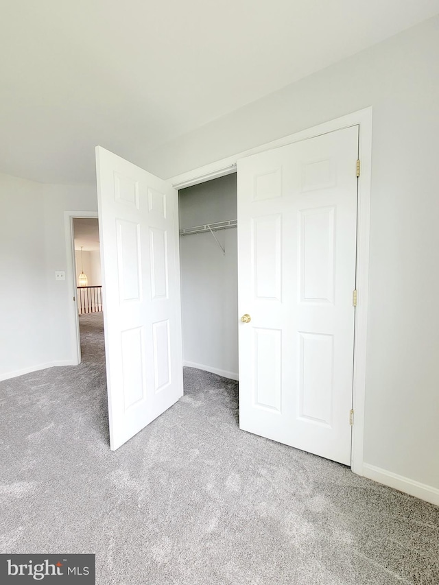 unfurnished bedroom with a closet, carpet, and baseboards