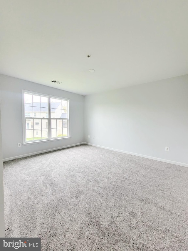 empty room featuring baseboards, visible vents, and carpet