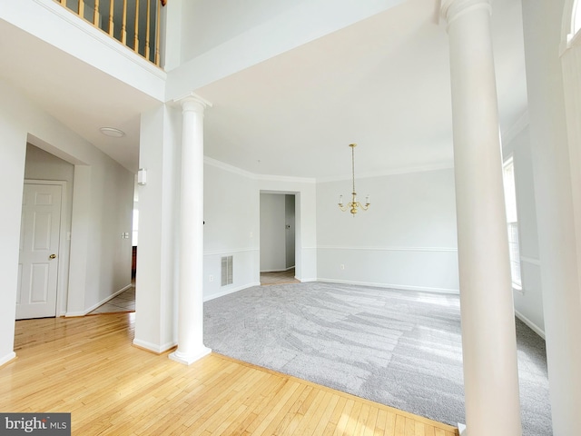 unfurnished room featuring visible vents, a chandelier, baseboards, decorative columns, and hardwood / wood-style floors