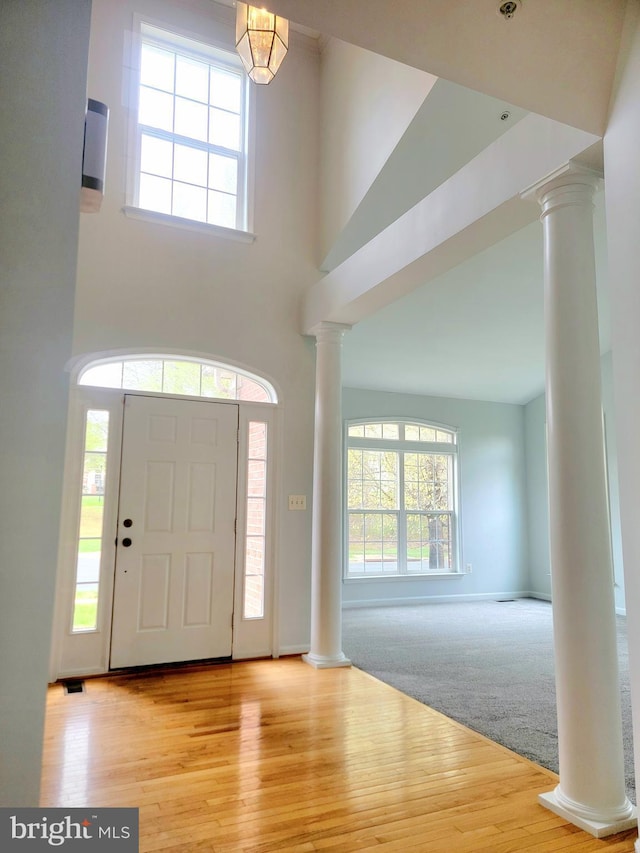 foyer with ornate columns, a high ceiling, and wood finished floors