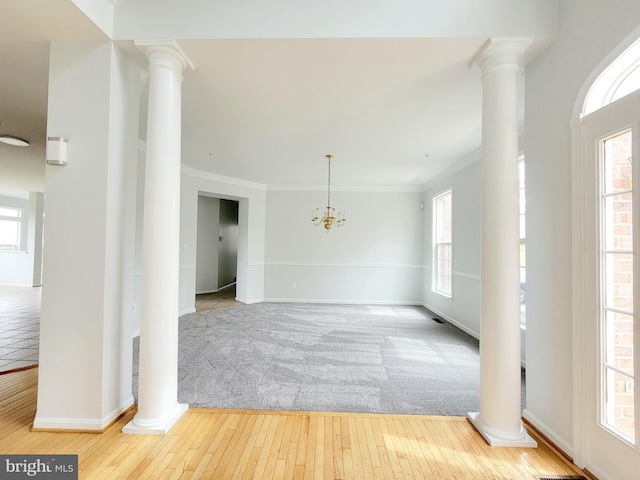 spare room featuring ornamental molding, hardwood / wood-style flooring, baseboards, and ornate columns