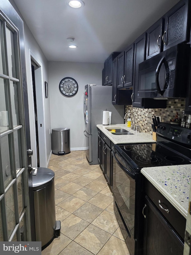 kitchen with backsplash, baseboards, light countertops, black appliances, and a sink