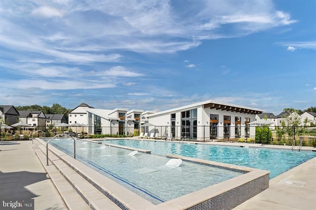 pool featuring a patio, fence, and a residential view