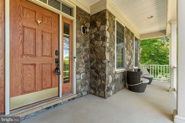 view of exterior entry with a porch and stone siding