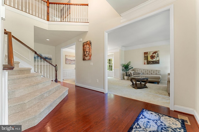 entrance foyer with stairway, hardwood / wood-style flooring, ornamental molding, baseboards, and visible vents