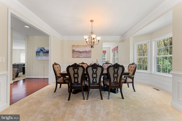 dining room featuring ornamental molding, visible vents, a wainscoted wall, and a notable chandelier
