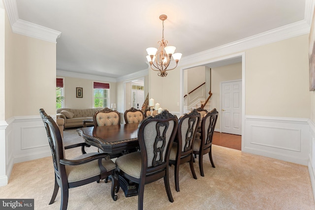 dining area featuring a chandelier, ornamental molding, wainscoting, and light carpet