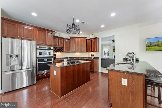 kitchen with dark stone countertops, stainless steel appliances, a sink, visible vents, and a peninsula