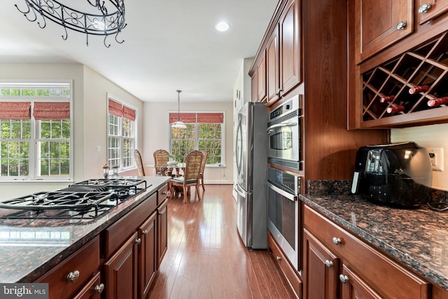 kitchen featuring dark stone counters, wood finished floors, black gas cooktop, and freestanding refrigerator