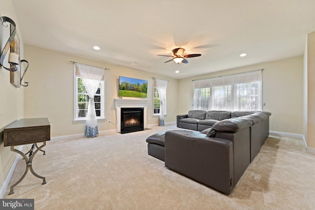living area featuring baseboards, a ceiling fan, carpet floors, and a fireplace with flush hearth