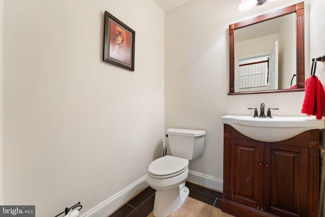 bathroom featuring baseboards, toilet, and vanity