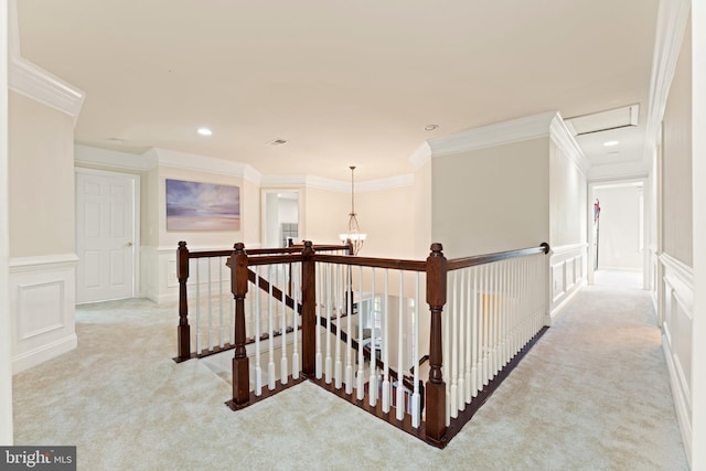 hall with a decorative wall, an upstairs landing, ornamental molding, and light carpet