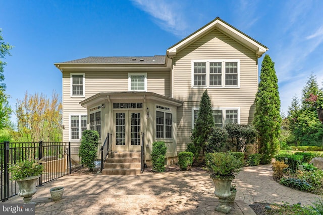 rear view of house with fence, entry steps, and a sunroom