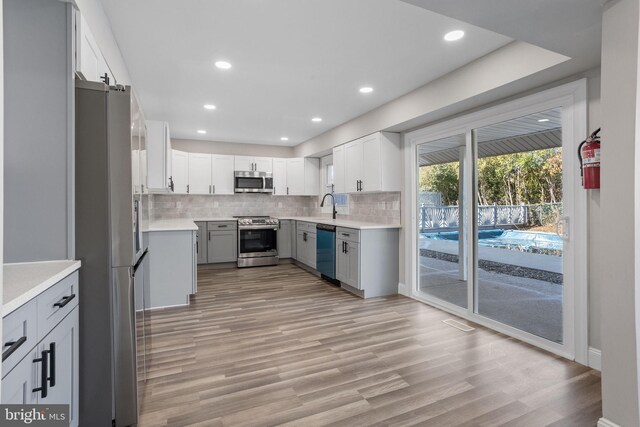kitchen featuring light countertops, backsplash, appliances with stainless steel finishes, and a sink