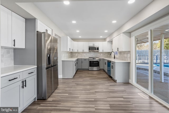 kitchen featuring light countertops, backsplash, light wood finished floors, and stainless steel appliances