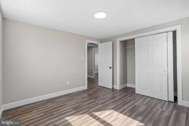 unfurnished bedroom with dark wood finished floors, visible vents, baseboards, and a closet