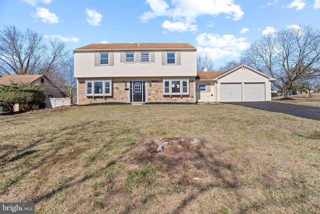 colonial inspired home with fence, aphalt driveway, a front yard, a garage, and stone siding